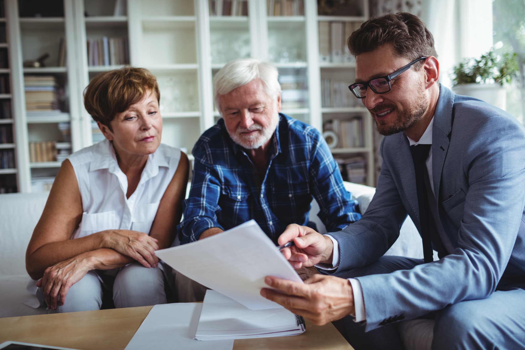 Senior couple planning their investments with financial advisor in living room